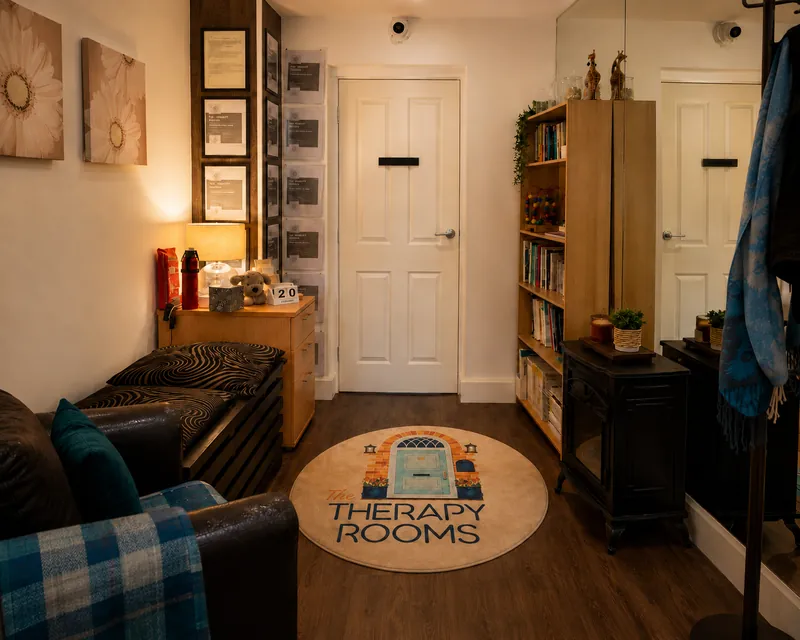 The entrance at The Therapy Rooms, with a round rug showing the practice's door logo, a seat, a lamp and a bookcase